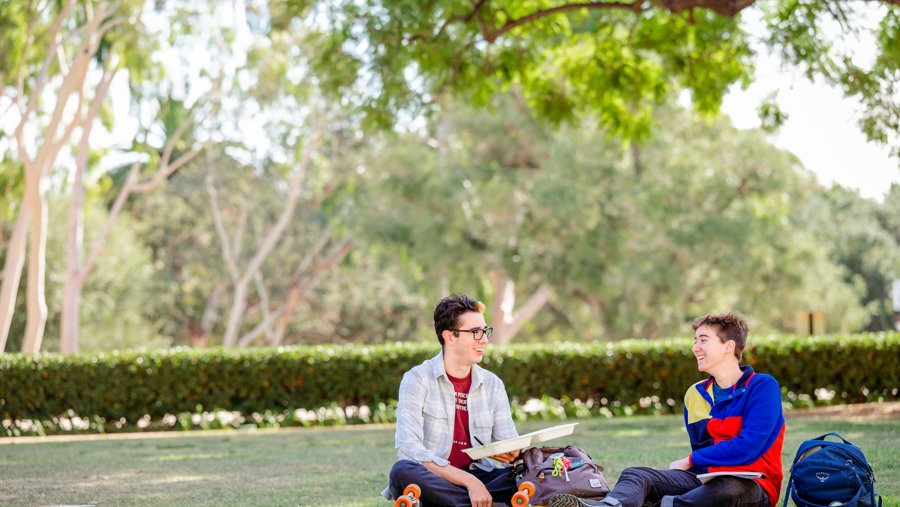 Two students smiling on a grassy area