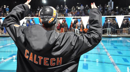 Swimmer with arms raised in front of a pool