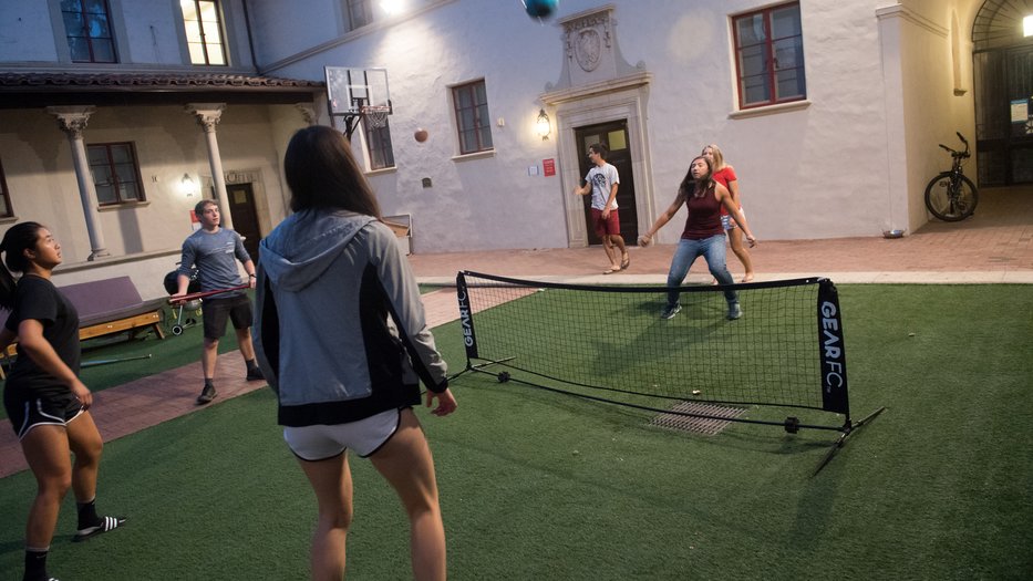 Students kick a ball back and forth over a net