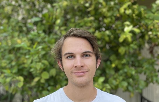 Profile photo of Miles Jones standing in front of a tree