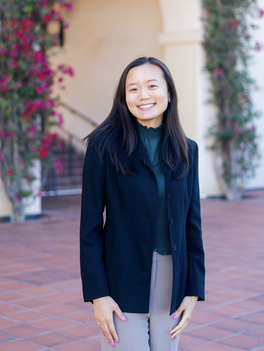 A headshot of Sydney Wuu in front of dark pink flowers
