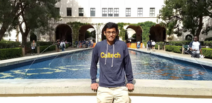 Caltech student Shri Deshmukh stands on campus in front of a fountain.
