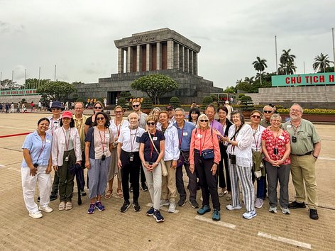 A group of tourists poses outside the tomb of Ho Chi Mihn in Vietnam