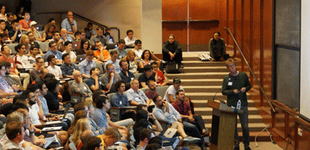 Beckman Institute Auditorium event with a speaker at lectern + audience