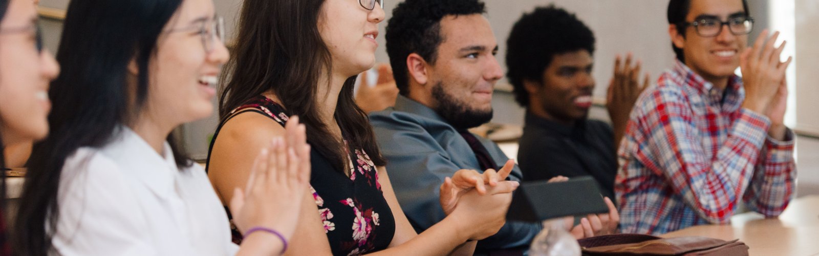 Students sitting in a row clapping