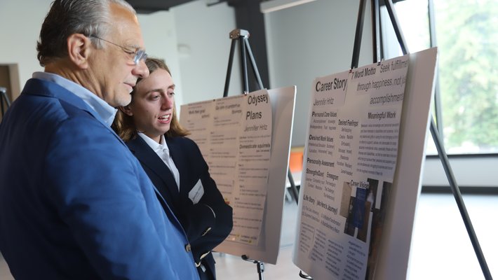 Jennifer Hritz (BS '23), presents her career plan to alumnus Phil Naecker (BS '76) at the 2023 Design Your Career final poster and mentor matching session.