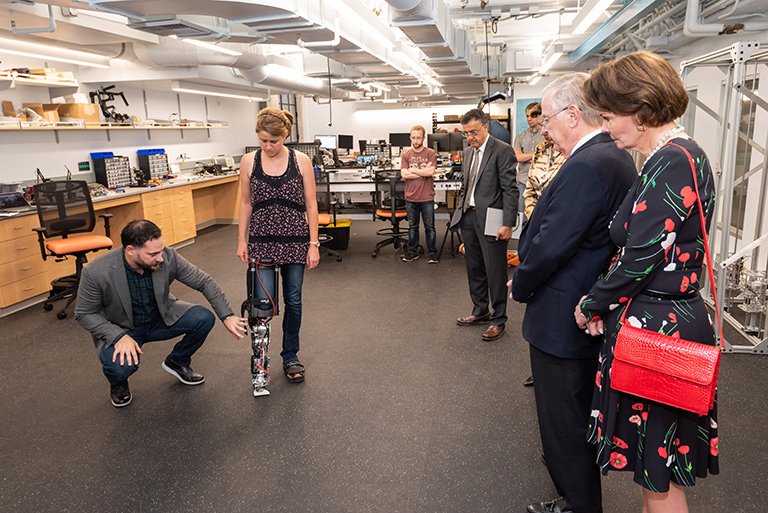 Kresa and Booth watch as graduate student Rachel Gehlhar demonstrates a novel prosthetic leg designed in Professor Aaron Ames's lab.