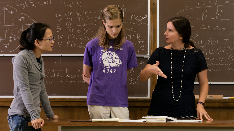 Professor Elena Mantovan speaks with two students.