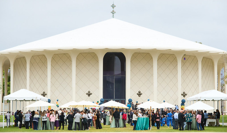 a crowd of people in front of a large white auditorium