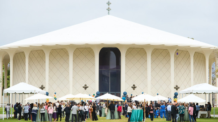 a crowd of people in front of a large white auditorium