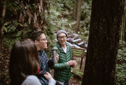 people in camping gear looking up in forest