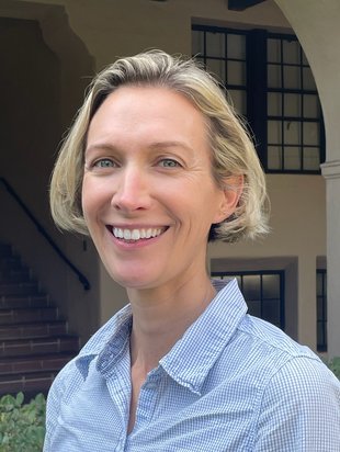 A woman with a short blonde bob wearing a blue checked button-down.