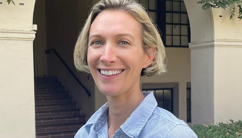 A woman with a short blonde bob wearing a blue checked button-down.