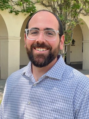 Bearded man with clear glasses smiling