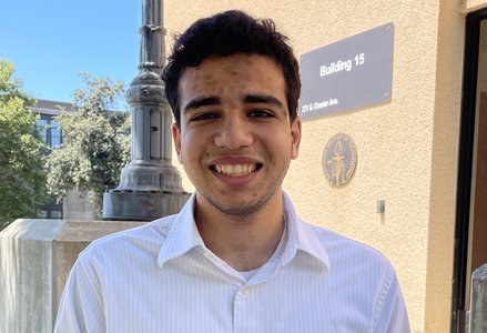 Young man with short curly hair wearing a white button-down shirt