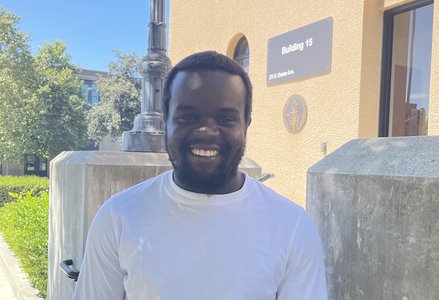 Young Kenyan man with a short beard wearing a long-sleeved white shirt