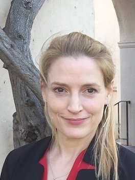 Woman with medium-length blond hair in a red blouse and a black blazer