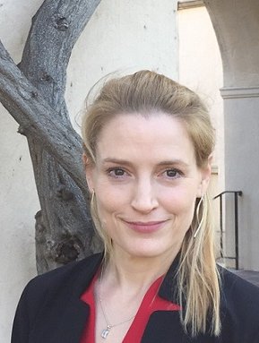 Woman with medium-length blond hair in a red blouse and a black blazer