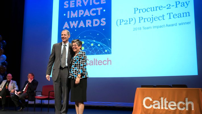 Tina Lowenthal (right), director of procurement for Purchasing Services, accepts the 2018 Team Impact Award on behalf of the P2P team.