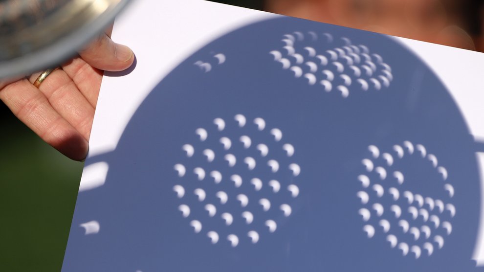 A kitchen colander is used to mimic the optics of a pinhole camera multiplied many times over to cast crescent-shaped images of the eclipse.
