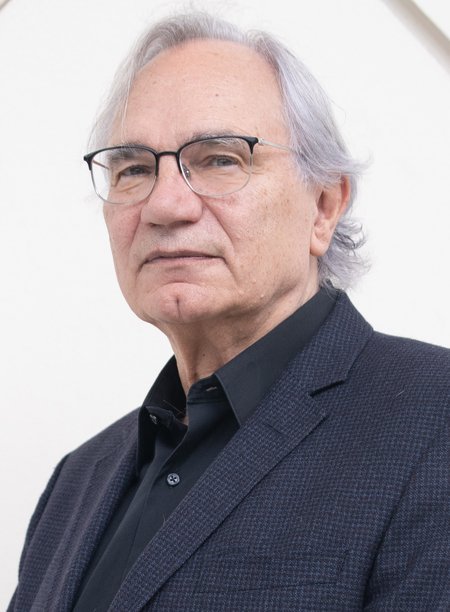 headshot of Richard Anderson, an older man with silver hair and glasses wearing a dark shirt and suit jacket.