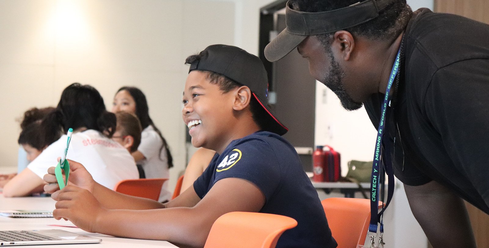 A person leans over a smiling child seated at a table