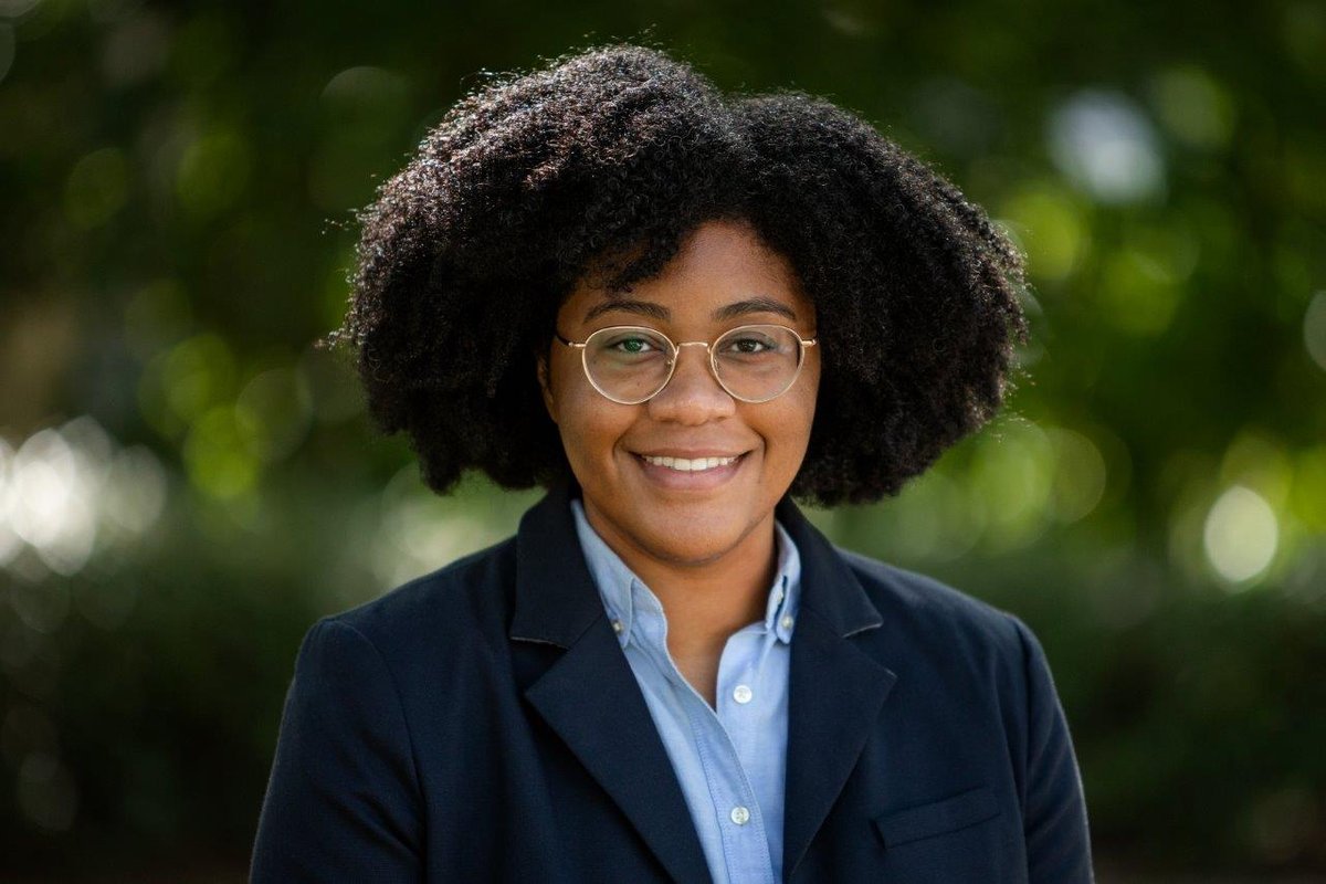 A portrait of Danielle Wiggins. She is outdoors and wears a blazer and button-down shirt.
