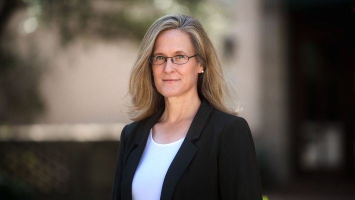 A portrait of Tracy Dennison. She is outside and wears a blazer.