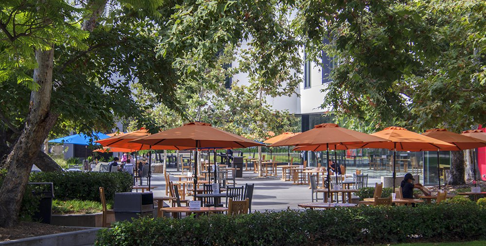 Photo of Caltech's campus featuring outdoor picnic tables covered by orange umbrellas