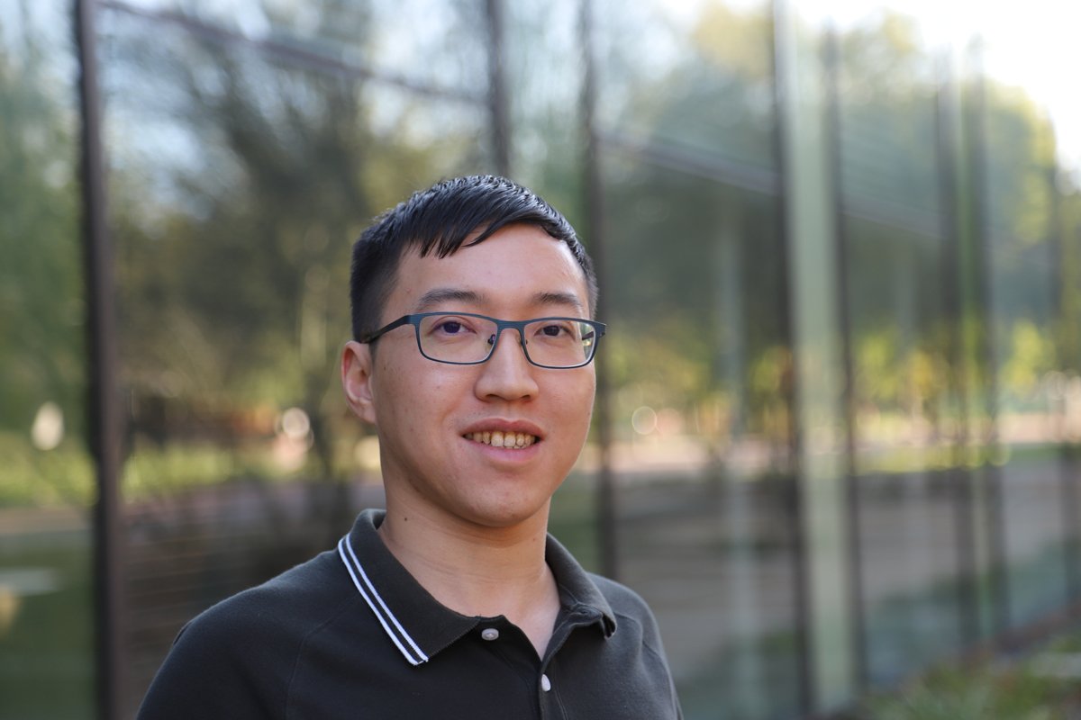 A portrait of Jiajie Chen. He wears a polo shirt and glasses and smiles at the camera.