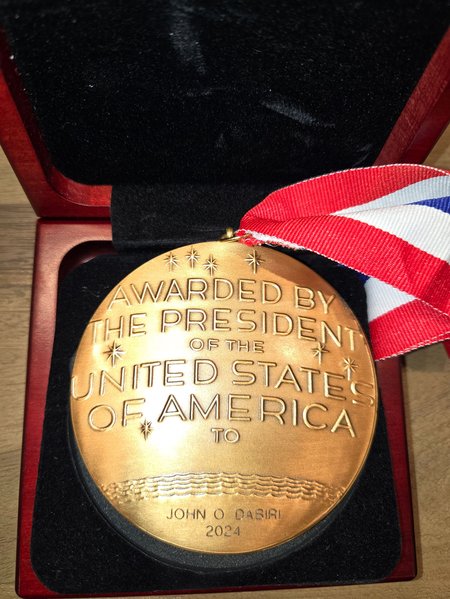 The back side of a National Medal of Science says, "Awarded by the President of the United States of America to John O. Dabiri 2024"