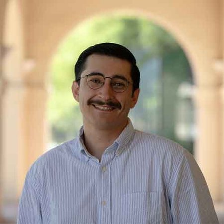 person in glasses posing in front of arches outdoors