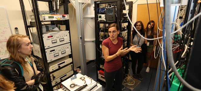 A scientist is seen talking to others in a lab full of equipment.