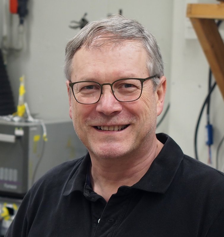 A portrait of Konstantinos Giapis. He smiles at the camera and wear a black polo shirt.