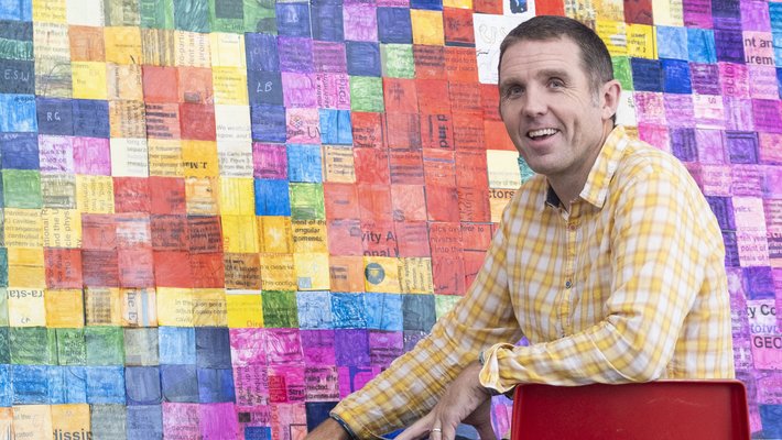 Calum Torrie seated alongside a mosaic of 1,156 science-themed pictures