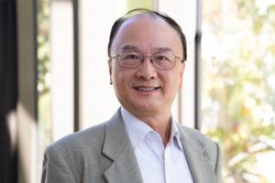 A portrait of Thomas Hou. He wears as suit and glasses and smiles at the camera.