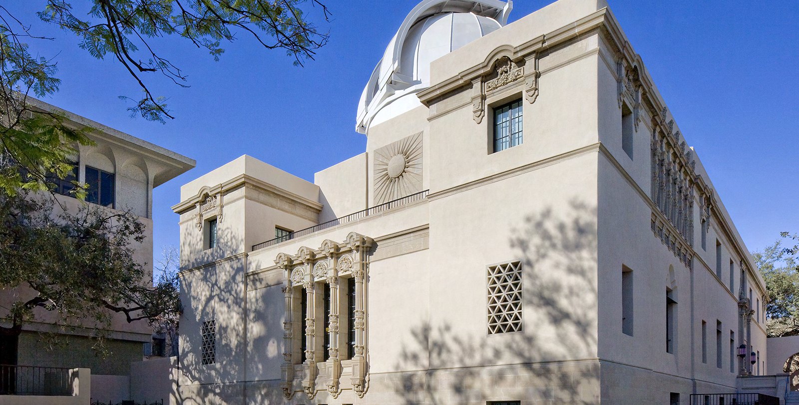 A cream-colored, three-story building with ornate sculptures