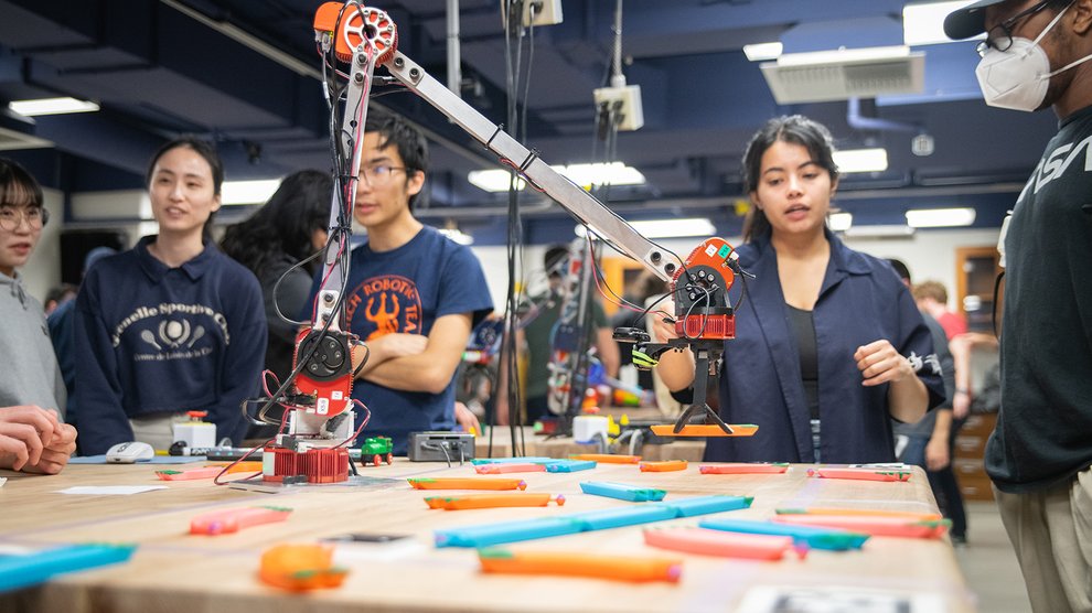 A robotic arm lifting a piece of toy train track.