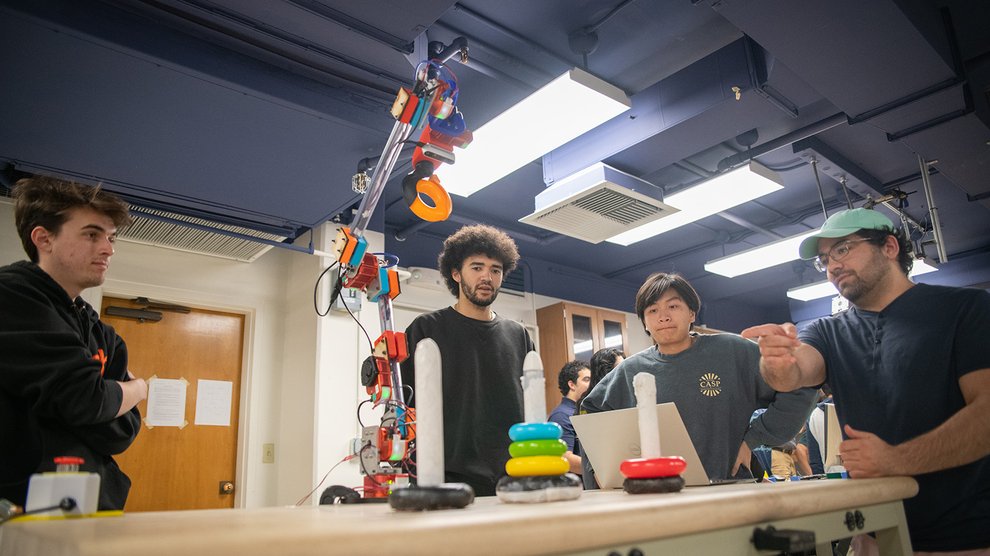 Students describe the work of their autonomous robotic arm, which is stacking up colored rings from a popular toddler toy.
