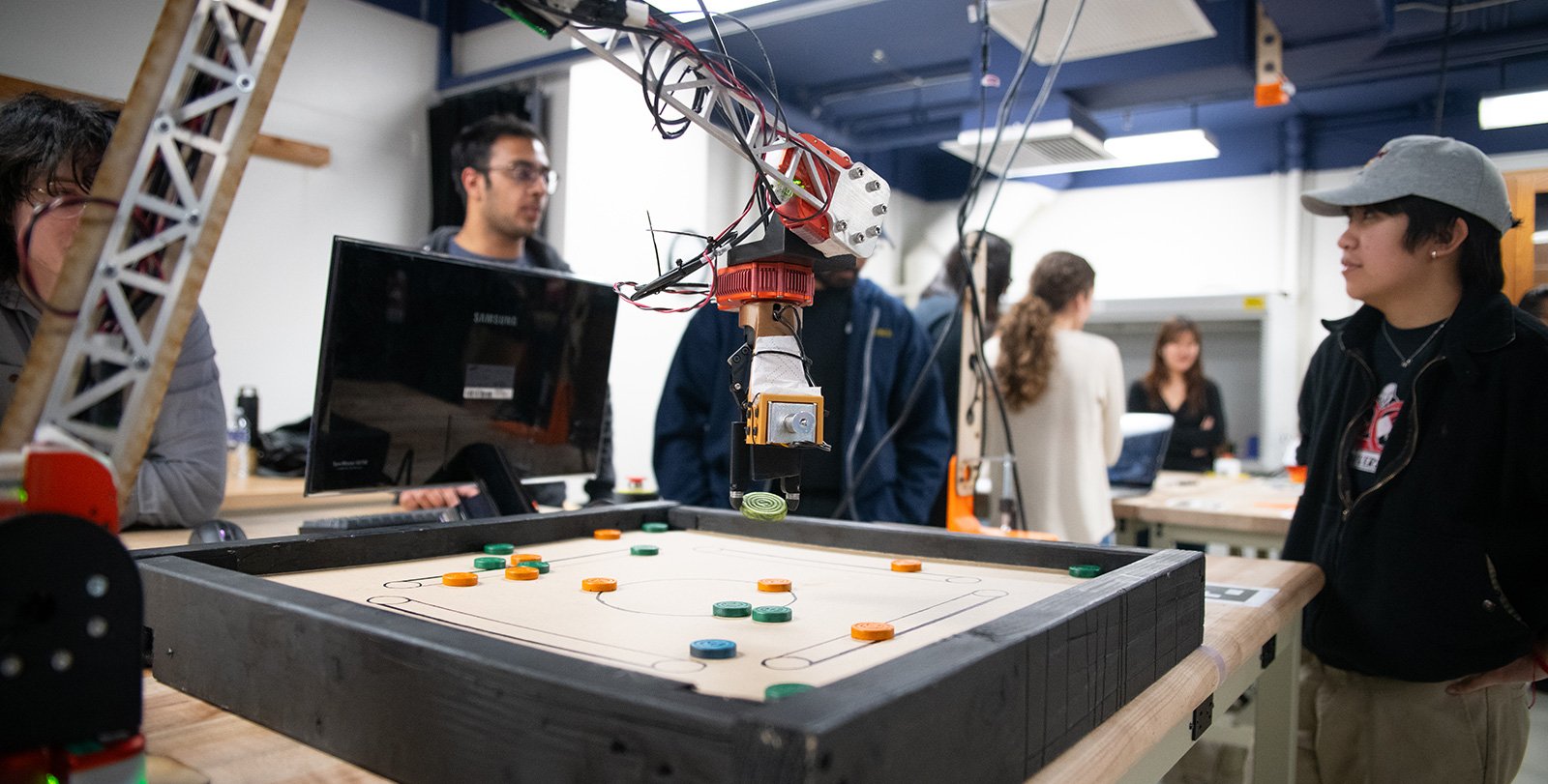 A robotic arm lifting a disk during a game of carrom.