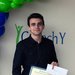 A person stands in front of a display wall with balloons and the words "Caltech Y"
