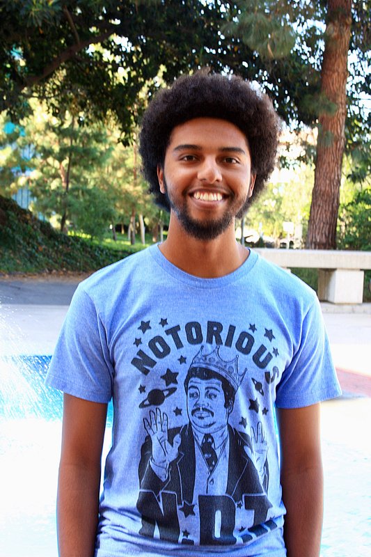 Graduate student Evan Nuñez stands, wearing a blue shirt