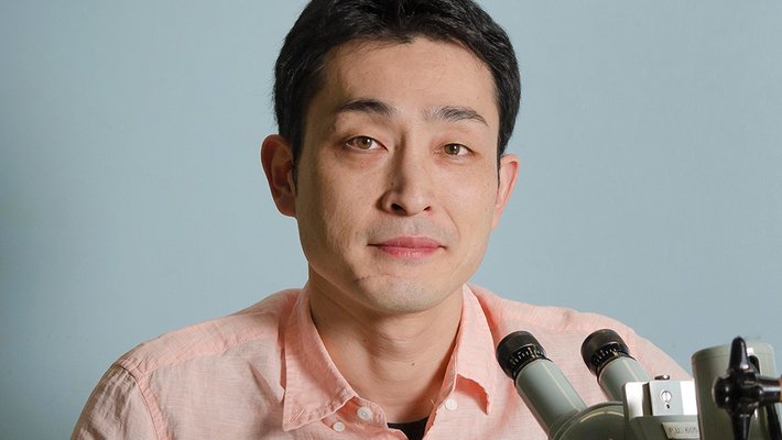 A man sits next to a microscope