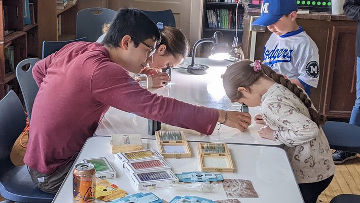 An adult helps a child use a microscope