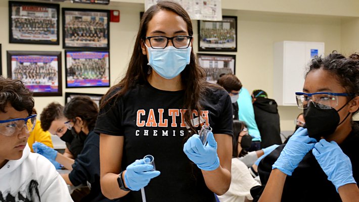 Melissa Ramirez demonstration chemistry experiment to two school-age teens