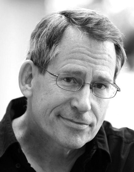 Head shot of Professor John Preskill. He is a middle-aged white man with glasses wearing a black shirt.
