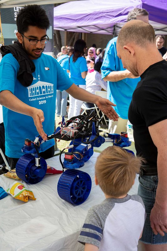 A Science for March volunteer shows guests a rover built using instructions from the Jet Propulsion Laboratory (JPL) Open Source Rover Project.