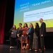 Members of the Student-Faculty Programs Office gather on stage with President Thomas Rosenbaum to receive the Team Impact Award.