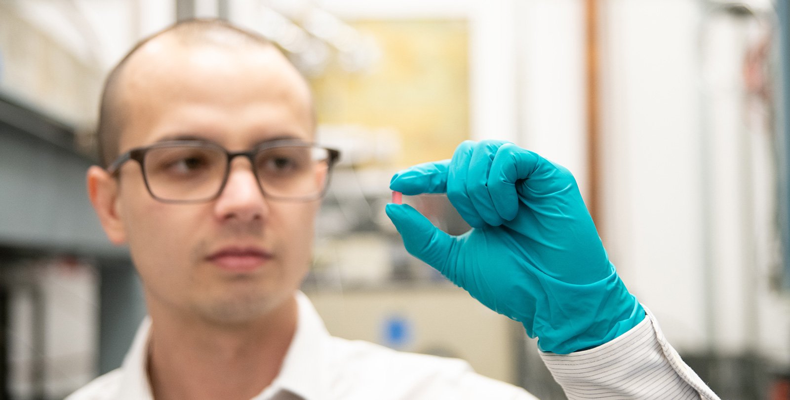 Christopher Simon holds a pink crystal made of lithium holmium yttrium fluoride.