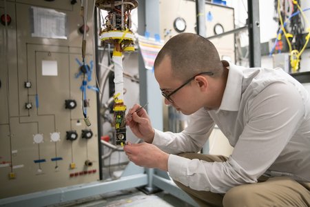 Christopher Simon is pictured in the lab working on an apparatus to make magnetic measurements at cryogenic temperatures.